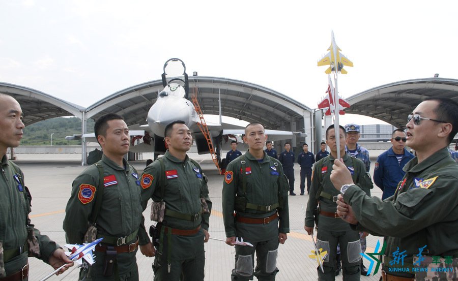 ↑艦載航空兵某部司令員戴明盟向飛行員演示空中飛行注意事項(xiàng)。
